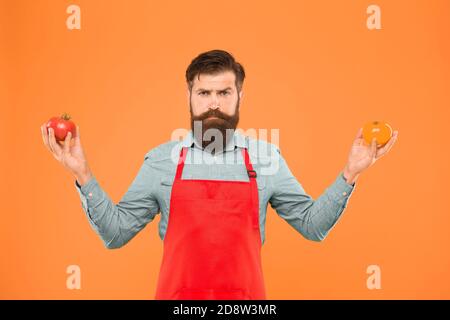 Essen Sie mehr Tomaten. Vorteilhaft für die Gesundheit der Haut. Gesundheitliche Vorteile der Tomate. Saftiges und süßes Gemüse. Brutales Kochen in der Schürze. Bärtiger Koch mit Tomaten. Ernährung schützen Sie sich vor Krebs. Stockfoto