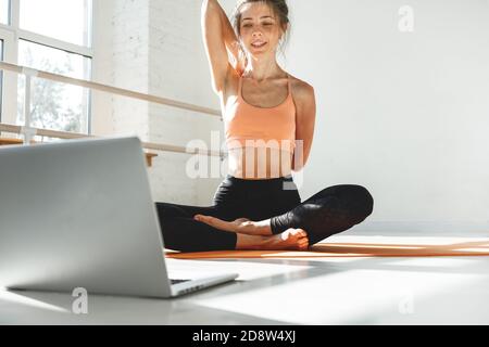 Fitnesstrainer mit virtuellen Yoga-Kurs mit Videoanruf auf Laptop. Remote Yoga Lehrer führt eine Lektion für Menschen Stockfoto
