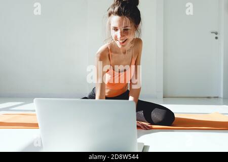 Fitnesstrainer nimmt online Yoga-Unterricht für Menschen zu Hause auf Videokonferenz. Remote Yoga Lehrer mit virtuellen Yoga-Klasse mit Videoanruf auf la Stockfoto