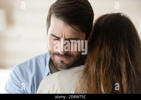 Mitfühlender tausendjähriger Mann umarmt junge, leidende Frau, die ihre Trauer teilt Stockfoto