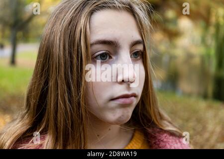 Nahaufnahme eines Teenage blonde Mädchen, das traurig aussieht. Draußen in der Herbstsaison. Stockfoto