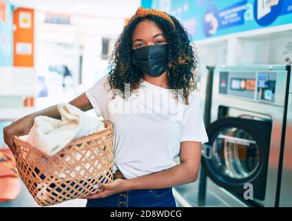 Junge afroamerikanische Frau mit lockigen Haaren lächelnd glücklich tun Hausarbeiten an der Wäscherei Stockfoto