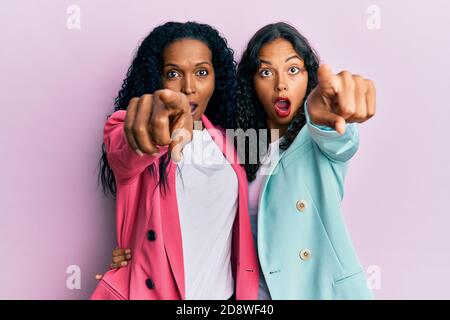 afroamerikanische Mutter und Tochter tragen Business-Stil zeigt mit Finger überrascht voraus, offenen Mund erstaunt Ausdruck, etwas auf der Vorderseite Stockfoto