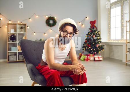 Positive lustige Weihnachtsmann in Hause festliche Kostüm sitzt in Sessel Stockfoto