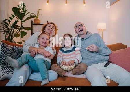 Lachende Familie beobachten Komödie zusammen auf der Couch in der Wohnzimmer Stockfoto