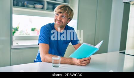 Junger ire lächelt glücklich Buch auf dem Tisch zu Hause sitzen. Stockfoto