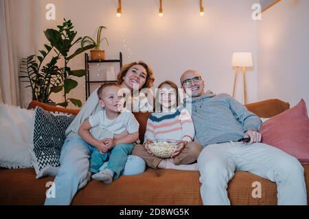 Glückliche Familie, die zusammen Fernsehen auf der Couch im Wohnzimmer Stockfoto