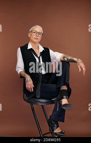 Junge elegante Frau mit kurzen blonden Haaren und Armen und Körper mit Tattoos bedeckt Stockfoto