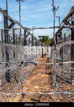 Barbwire sichere Grenze Engineering Schutzwand. Zaun mit Metallbarbe Stromkabel des Gefängnisses. Kokosnuss Gefängnis Phu Quoc Insel Vietnam Krieg m Stockfoto