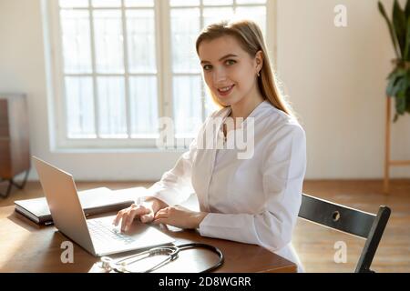 Portrait von angenehmen jungen Dame Arzt mit Laptop am Arbeitsplatz Stockfoto