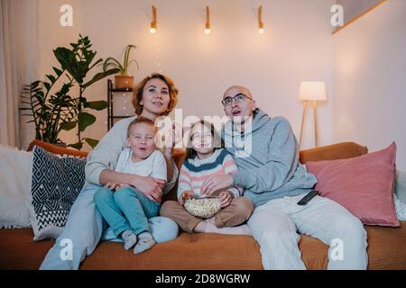 Eingetaucht Familie Fernsehen zusammen auf der Couch im Wohnzimmer Stockfoto