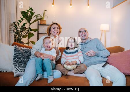 Amüsiert Familie beobachten Comedy zusammen auf der Couch in der Wohnzimmer Stockfoto