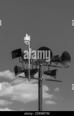 Tannoy oder Lautsprechersystem und Überwachungskamera gegen einen dunklen Himmel - monochrom. Dystopische Vorschläge. Stockfoto