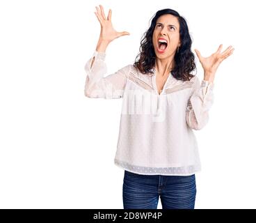 Junge schöne hispanische Frau in Freizeitkleidung verrückt und verrückt schreien und schreien mit aggressiven Ausdruck und Arme angehoben. Frustration conce Stockfoto