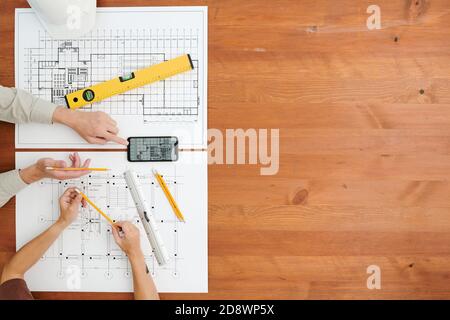 Übersicht über die Hände von zwei Ingenieuren oder Bauherren, die neue machen Skizzen nach Tabelle Stockfoto