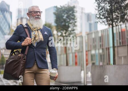 Glücklicher Hipster Senior Business Mann zu Fuß zur Arbeit beim Trinken Kaffee - Fokus auf Gesicht Stockfoto
