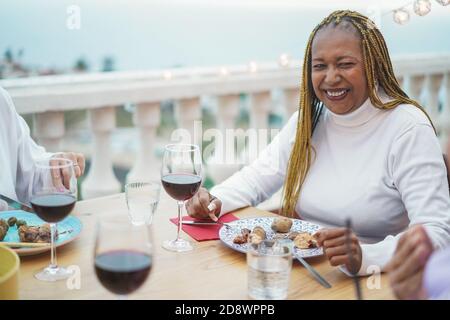 Afrikanische ältere Frau, die mit Freunden zu Abend gegessen und Wein getrunken hat Beim Barbecue im Restaurant - Fokus auf Gesicht Stockfoto