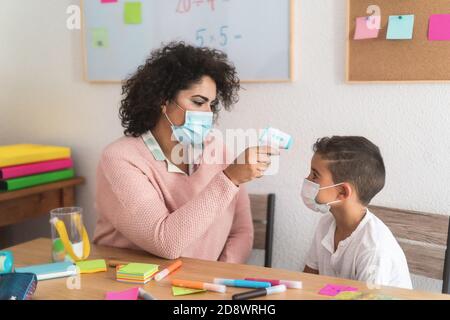 Lehrer, der die Temperatur des Kindes mit einem Infrarot-Thermometer in der Schule überprüft - Konzentrieren Sie sich auf das Gesicht der Frau Stockfoto