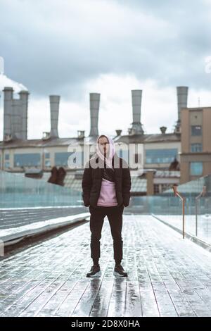 Schöner Casual Mann in Windbreaker auf einem der hohen Brücke industriellen Hintergrund stehen. Stockfoto