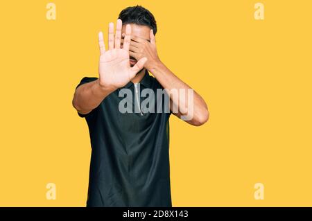 Junger Mann mit Bart tragen Sportkleidung, die Augen mit Händen und tun Stop-Geste mit traurig und Angst Ausdruck. Verlegen und negative Konzept Stockfoto