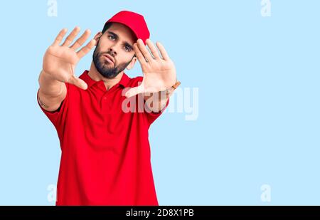 Junge gutaussehende Mann mit Bart tragen Lieferung uniform tun Rahmen mit Händen Handflächen und Finger, Kamera Perspektive Stockfoto