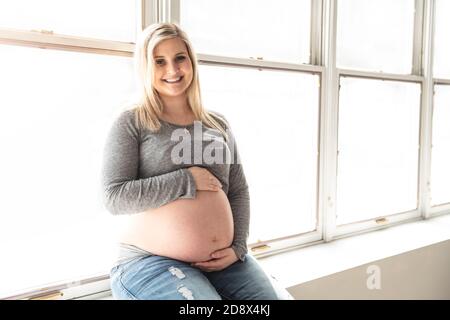 Die schwangere Frau streichelt ihren Bauch zu Hause Stockfoto