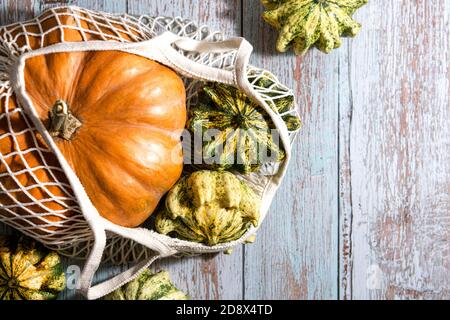 Thanksgiving Hintergrund, Komposition mit Herbstkürbissen im Einkauf umweltfreundliche Tasche auf Holzhintergrund. Herbsturlaub, Kürbisernte. Gemüse der Saison. Keine Verschwendung. Gesunde natürliche Lebensmittel. Stockfoto