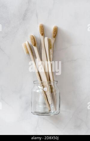 Komposition mit biologisch abbaubaren Bambus-Zahnbürsten auf Marmorboden. Nachhaltig, Null Abfall, plastikfrei, Lifestyle-Konzept. Umweltfreundliches Mundhygiene-Zubehör. Flach liegend, Draufsicht. Stockfoto