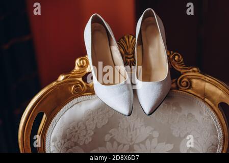 Weiße Luxus-Brautschuhe auf einem Vintage-Stuhl. Stockfoto