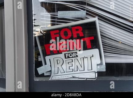 Ein schräges 'for Rent'-Schild in einem Fenster mit schiefen, gebrochenen Jalousien Stockfoto