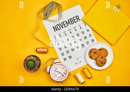 November-Kalender auf hellgelben Desktop. Der helle Arbeitsplatz eines Schneidermeisters oder Modedesigners Stockfoto