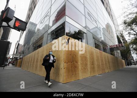 Peking, USA. November 2020. Eine Frau geht am 1. November 2020 an einem vernagelten Laden auf der Fifth Avenue in New York, USA, vorbei. Die Schritte kommen, da Einzelhändler versuchen, sich in den kommenden Tagen vor Plünderungen oder anderen Unruhen zu schützen. Quelle: Wang Ying/Xinhua/Alamy Live News Stockfoto