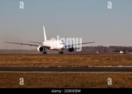 Weißes Breitkörper-Passagierflugzeug bewegt sich hinter dem Follow-me-Car ein Der Haupttaxiway Stockfoto