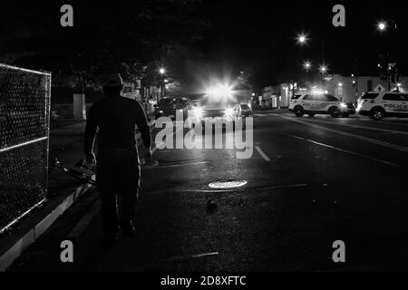 Ein Mann geht bei Protesten gegen die Polizei über den Tod von Karon Hylton, Washington, DC, USA, mit blinkenden Lichtern auf Polizeiautos zu Stockfoto