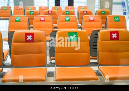 Reihe leerer Sitzbankstühle im öffentlichen Verkehrsterminal mit sozialer Distanzierung während der Coronavirus-Pandemie. Covid-19 Sicherheitshinweis zur Vermeidung von Virenverbreitung Konzept. Stockfoto