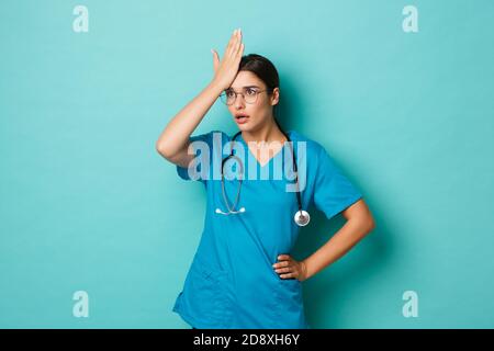 Coronavirus, Pandemie und soziales Distanzierungskonzept. Bild von verärgerten Ärztin in Peelings und Brille, Facepalm und schauend geschockt, stehend Stockfoto