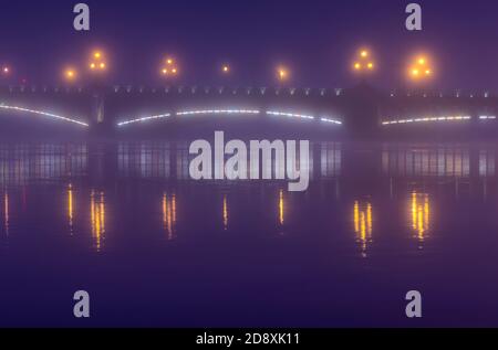 Neblige Landschaft der Dreifaltigkeitsbrücke mit glühenden Laternen in der blauen Stunde (Sankt Petersburg, Russland) Stockfoto