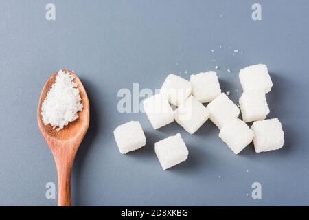 Weißer Zuckerwürfel süße Lebensmittel Zutat und Zucker in Löffel, Studio erschossen auf einem grauen Hintergrund isoliert, Minimal Gesundheit hohes Blutrisiko von Diabetes und c Stockfoto