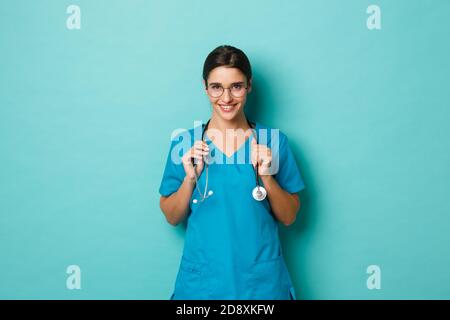 Coronavirus, Pandemie und soziales Distanzierungskonzept. Nahaufnahme einer selbstbewussten, schönen Ärztin, lächelnd und mit Brille in die Kamera schauend Stockfoto