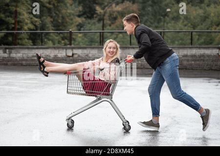 Junges Paar mit Spaß auf Shopping-Trolley. Glücklicher Mann schieben Warenkorb mit seinem Freund innen Stockfoto