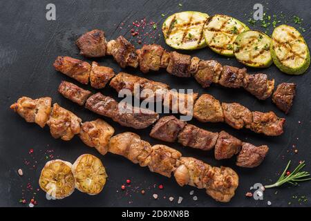 Verschiedene Kebabs auf einem schwarzen Steinteller mit gebraten Knoblauch Stockfoto