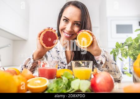 Frau hält rot und gelb geschnittenes Orange in den Händen mit frischen Säften vor sich. Stockfoto