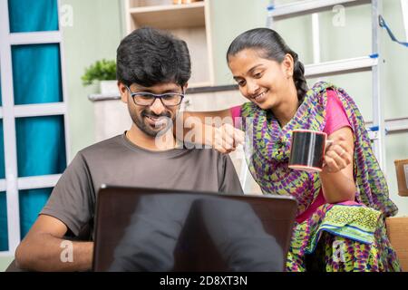 Paar bei neu gekauften Wohnung oder Haus suchen oder planen für Home-Verbesserung Produkte auf Laptop, während zusammen sitzen in unmöbliertem Zimmer. Stockfoto