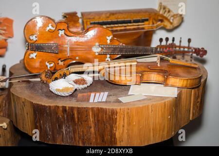 Barocke Holzvioline auf einem Baumstamm in der Nähe anderer Instrumente. Stockfoto