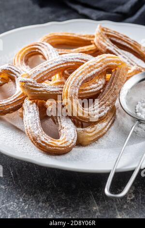 Leckere frittierte Churros mit Zuckerpulver auf dem Teller. Stockfoto