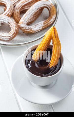 Leckere frittierte Churros mit Zuckerpulver und Schokoladendip auf weißem Tisch. Stockfoto