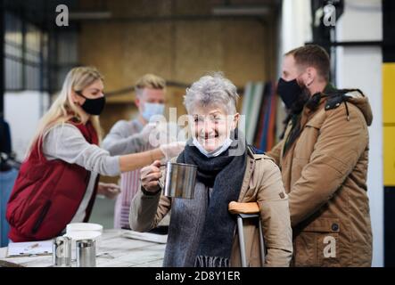 Freiwillige servieren heiße Suppe für Obdachlose in Gemeinschaft wohltätige Spende Zentrum, coronavirus Konzept. Stockfoto