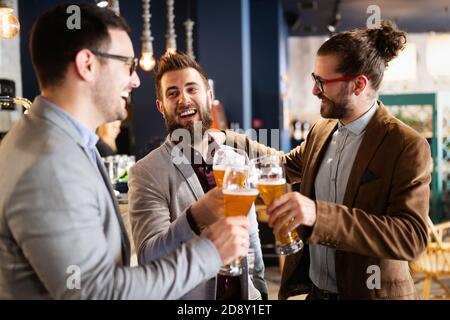 Junge Geschäftsleute trinken Bier, reden und lächeln, während sie sich in der Kneipe ausruhen Stockfoto