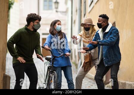 Gruppe von jungen Menschen mit Fahrrad im Freien in der Stadt, reden. Coronavirus-Konzept. Stockfoto