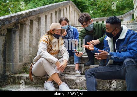 Gruppe von jungen Menschen im Freien in der Stadt, mit smartpone. Coronavirus-Konzept. Stockfoto